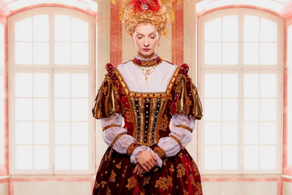 A queen wearing a red and gold royal gown
