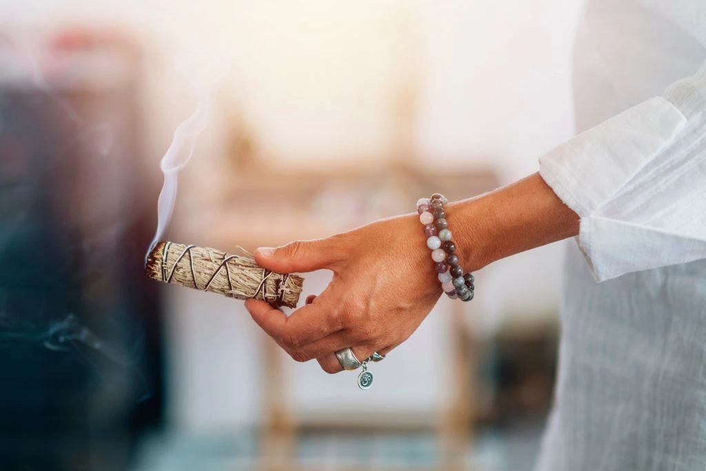 A person holding a burning dried sage
