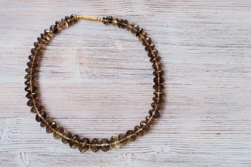 Smoky Quartz crystal bracelet placed on a grayish platform