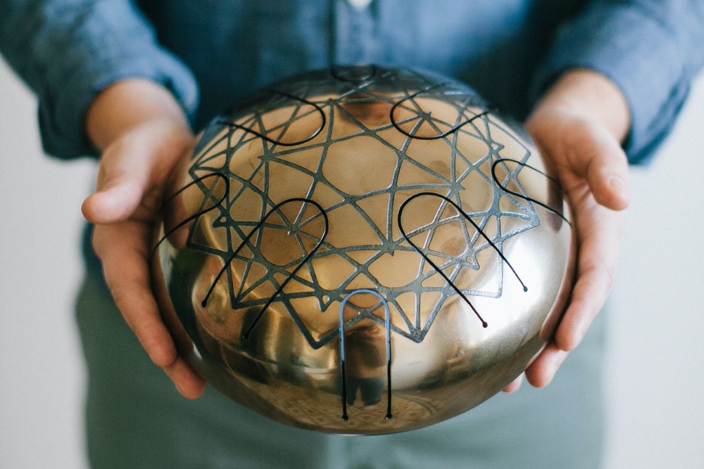 a man holding a golden tongue drum