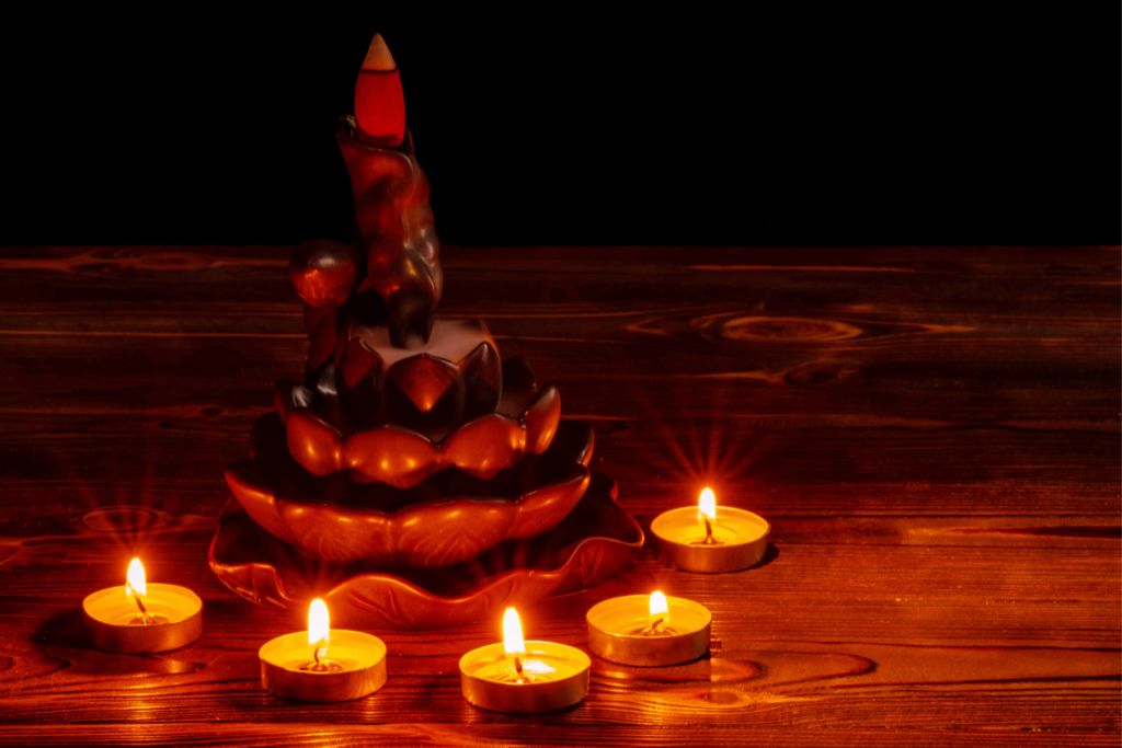 burning backflow incense cone on a lotus flower incense plate with 5 tiny candles