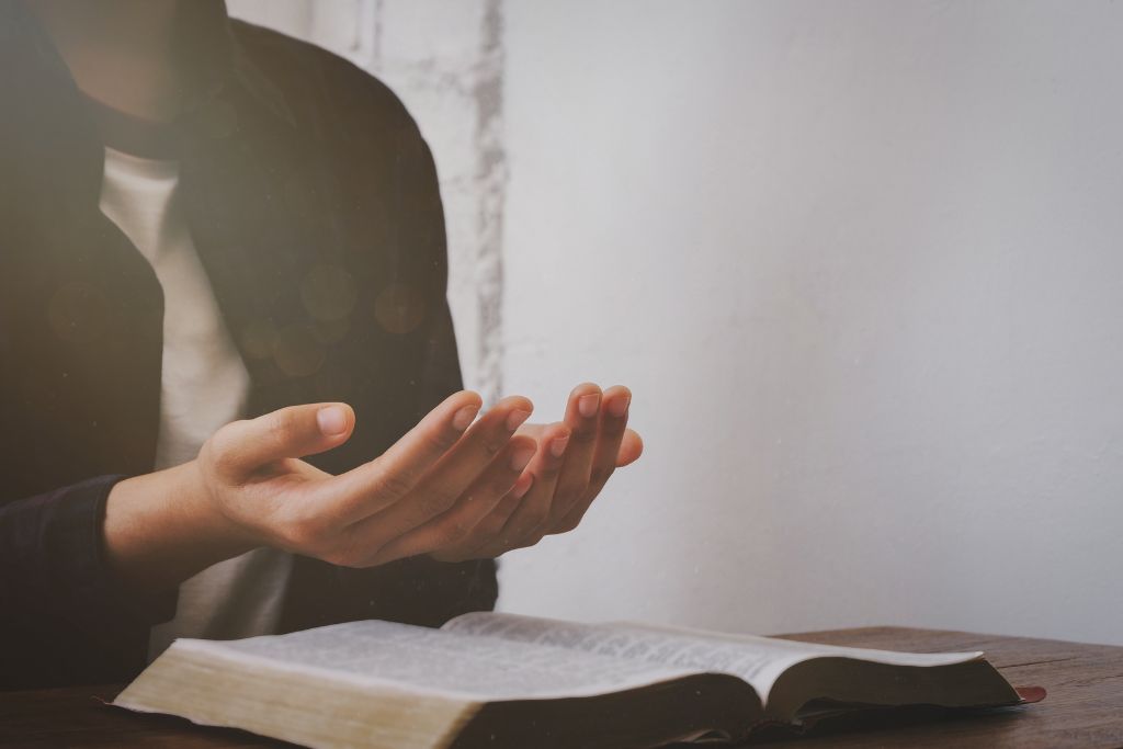 a person lifting his/her hands in front of the bible