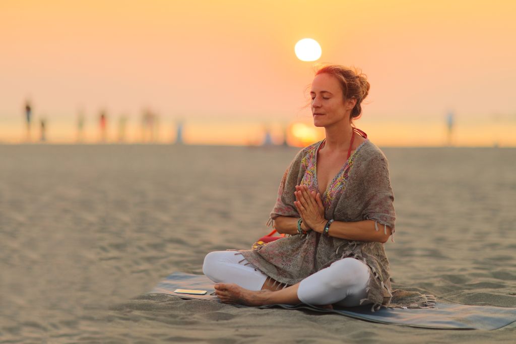 A woman is meditating at the beach