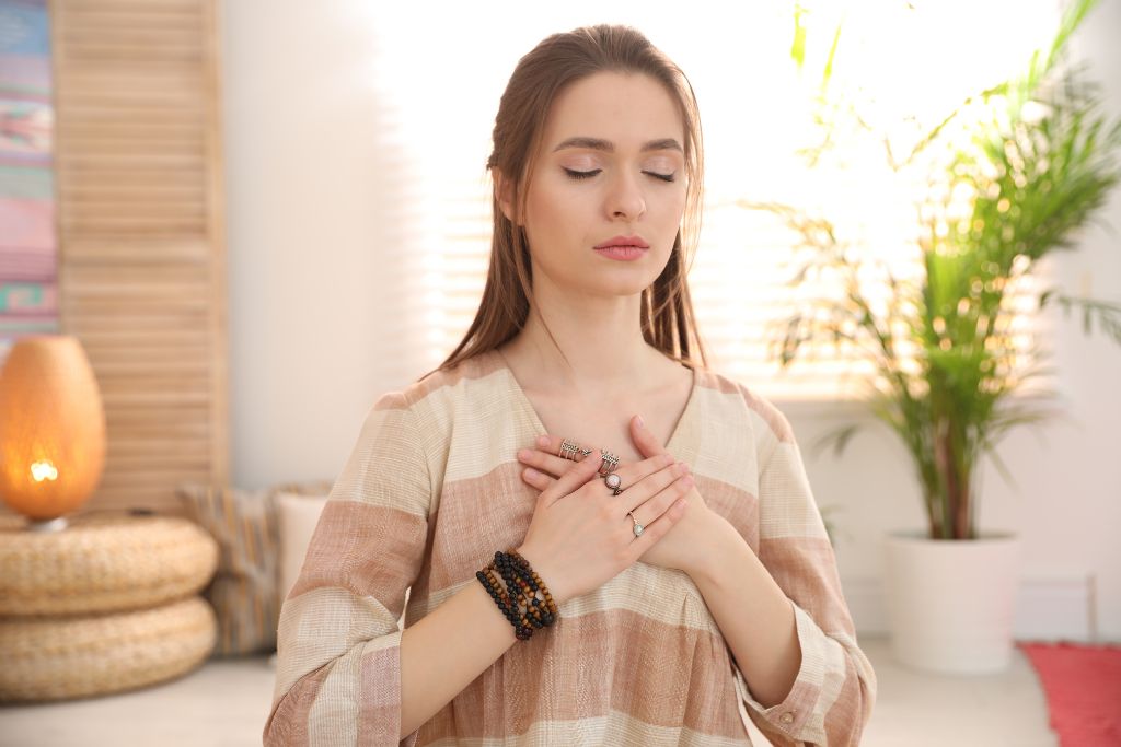 woman holding her chest with her 2 hands in a room