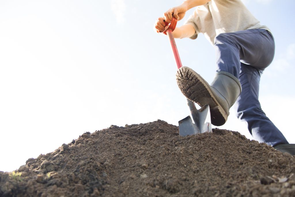 man digging dirt with shovel