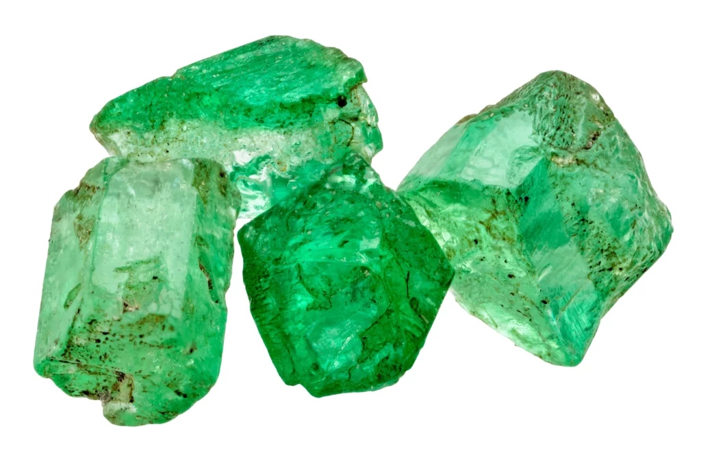 4 uncut emeralds in a white background