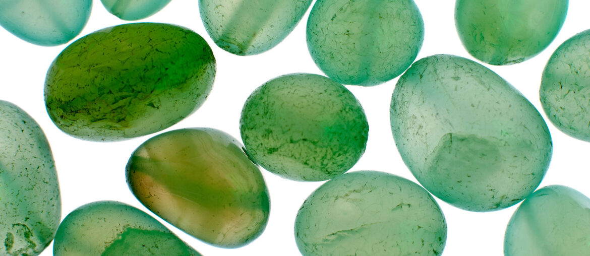 green aventurine beads scattered on a white background