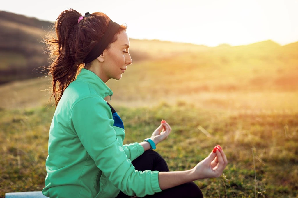 Woman meditating on a field of grass background