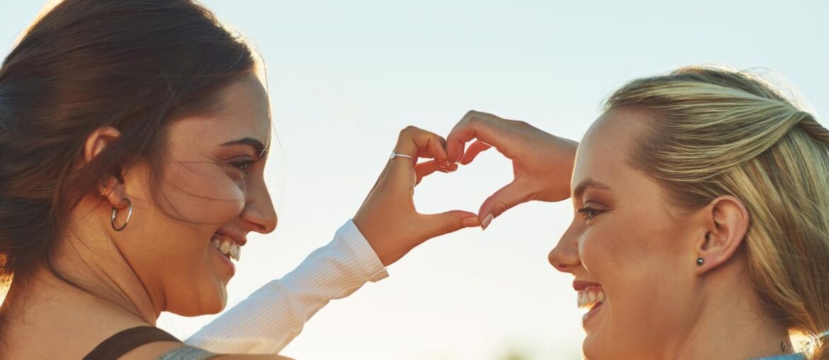 2 female model making a heart shape with their hands