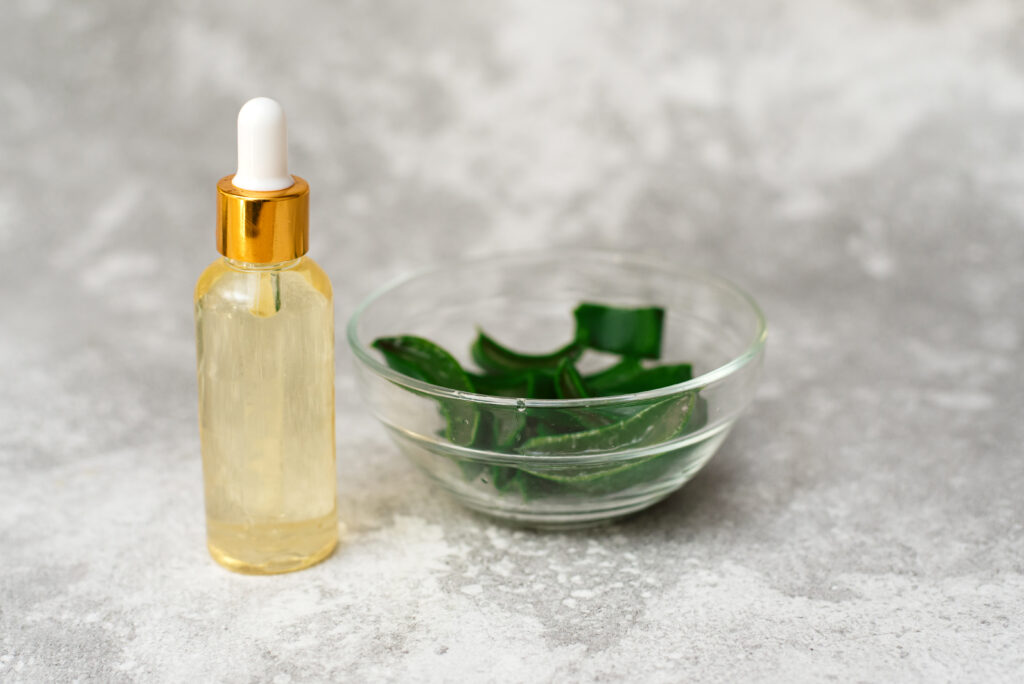 a bottle of essential oil with a bowl of herbs