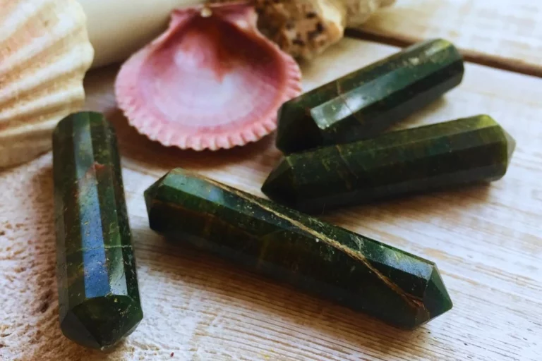 green aventurine stone with sea shells on its side placed on a wooden table