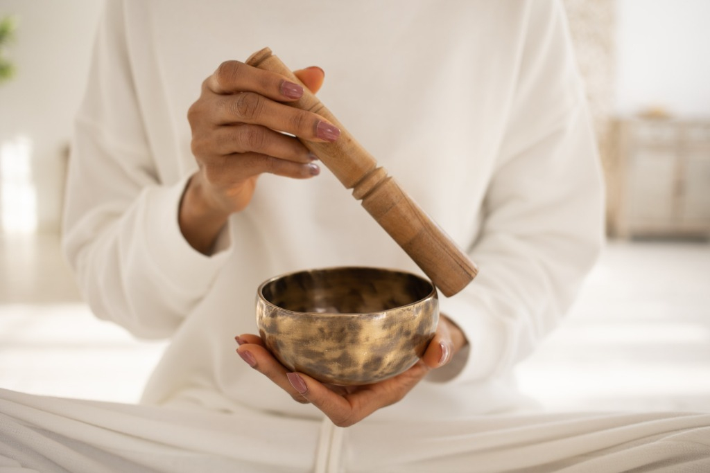 Woman with white long sleeves holding a tibetan singing bowl