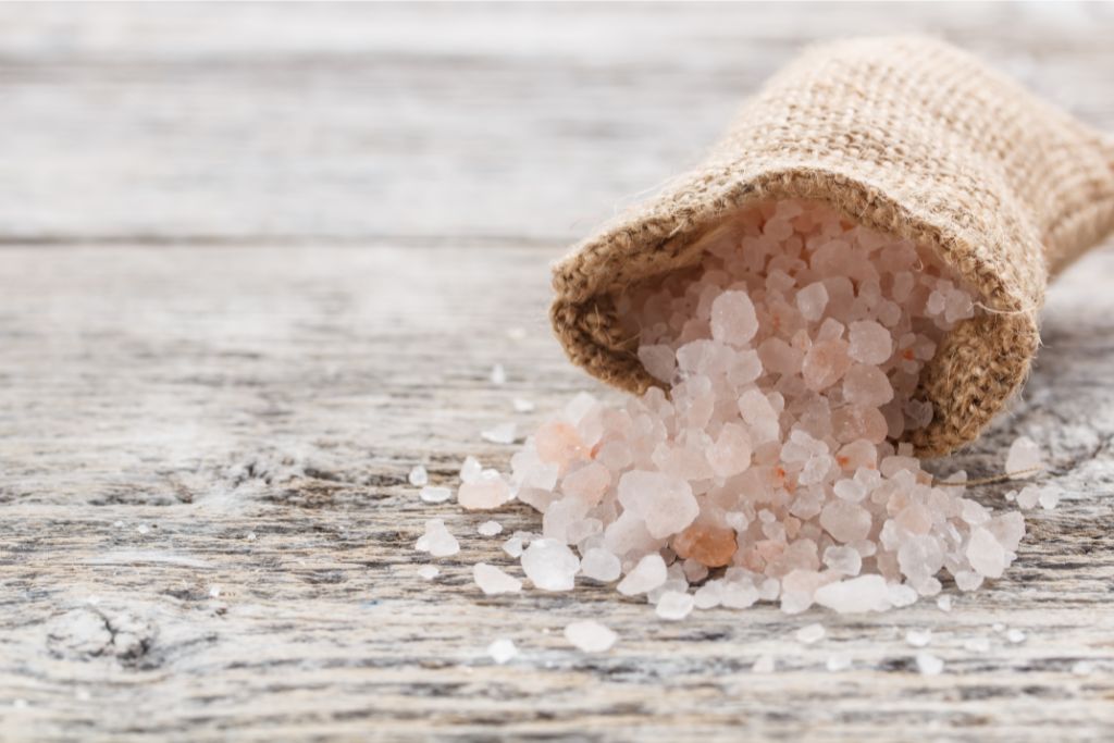 pink salt crystals pouring out of a jute bag