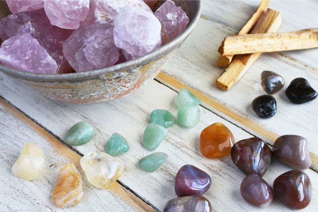 bowl or rose quartz and other crystals on a wooden table