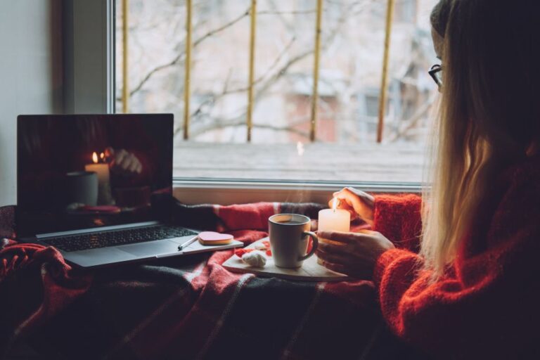 woman lighting candle in front of her laptop