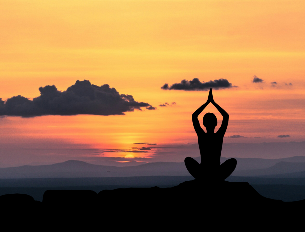 silhouette of a meditating woman with a sunset background
