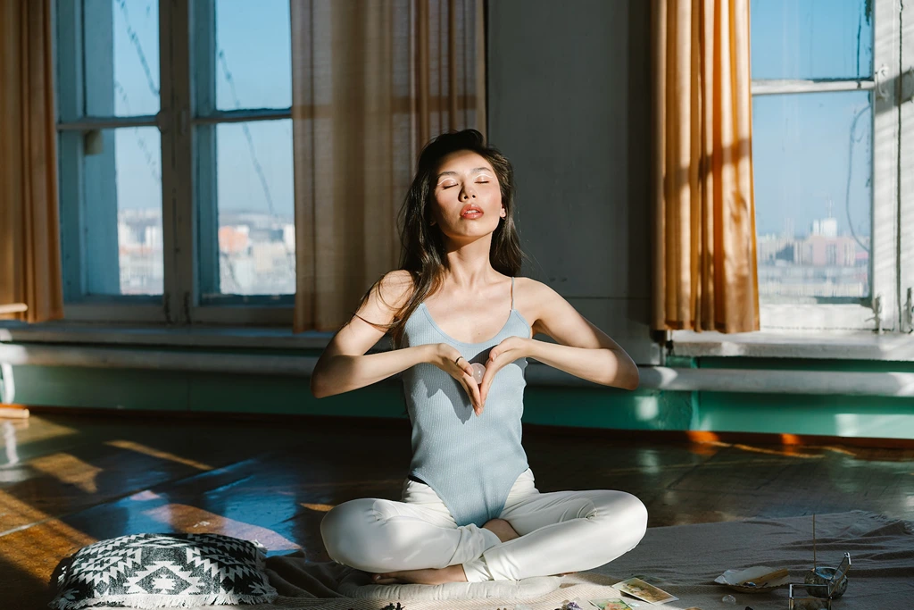 woman meditating while holding a rose quartz ball near her heart chakra