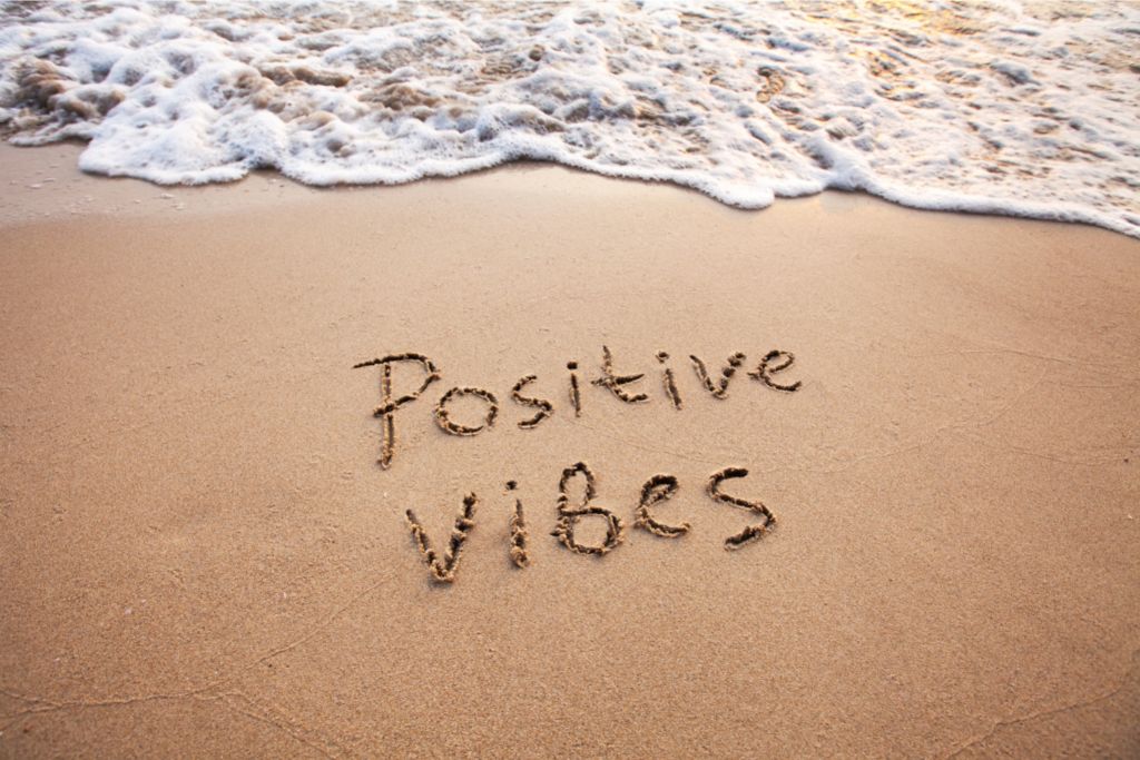 positive vibes written on the sand