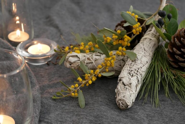 sage smudge sticks with dried flowers and candles on a wood table
