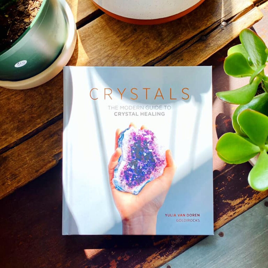 Crystals: The Modern Guide to Crystal Healing by Yulia Van Doren placed on top of a coffee table