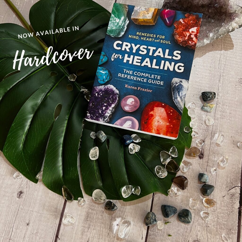 Crystals for Healing book by Karen Frazier together with polished stones placed on a wooden table
