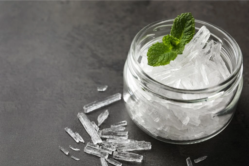 menthol crystals in a bottle with mint leaves