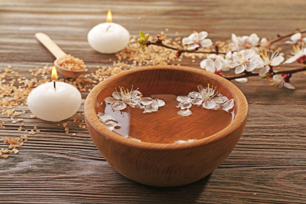 wooden bowl of water with flowers and candles