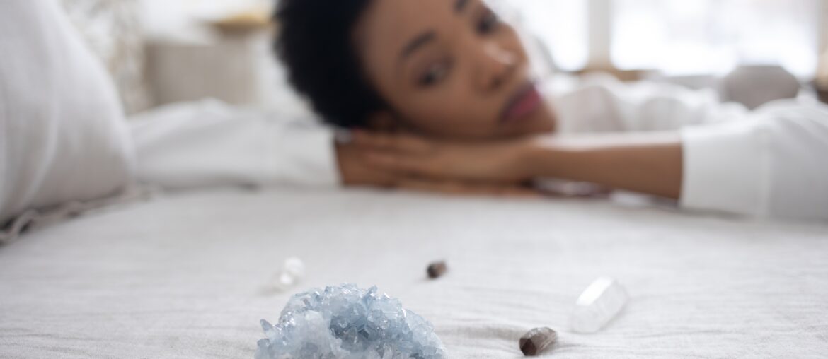 woman looking at crystal on top of bed