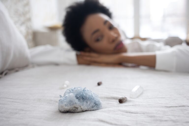 woman looking at crystal on top of bed