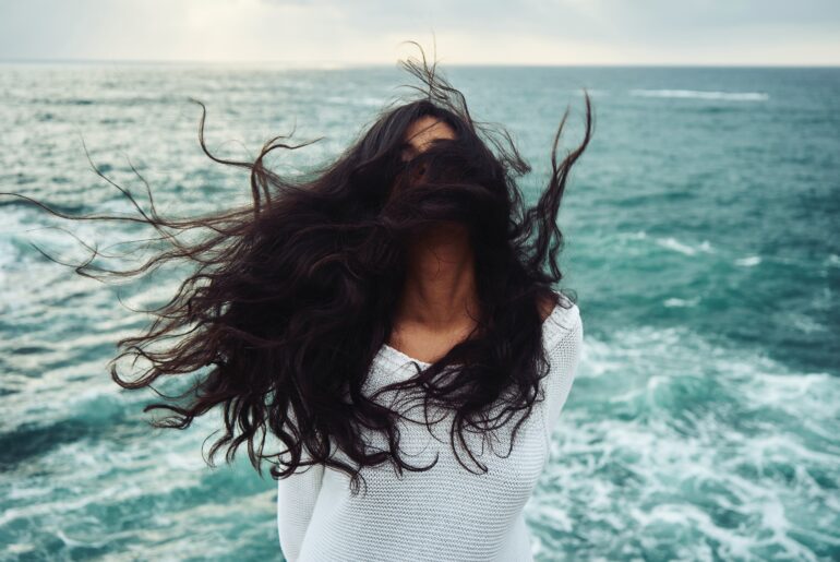 girl with long curly hair with ocean background
