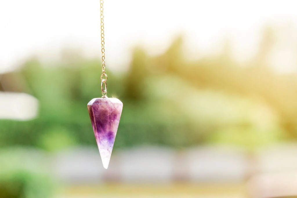 Amethyst Pendulum Crystals on a blurred background