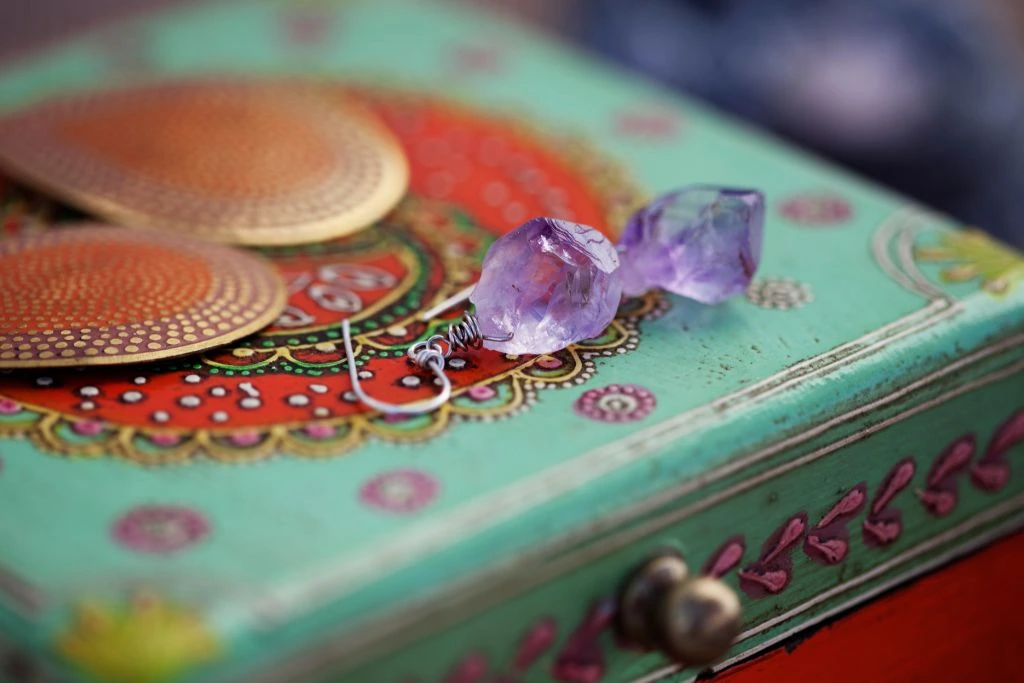 Amethyst earrings placed on top of a colorful jewelry box