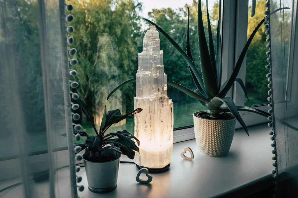 selenite tower lamp on a window sill with plants