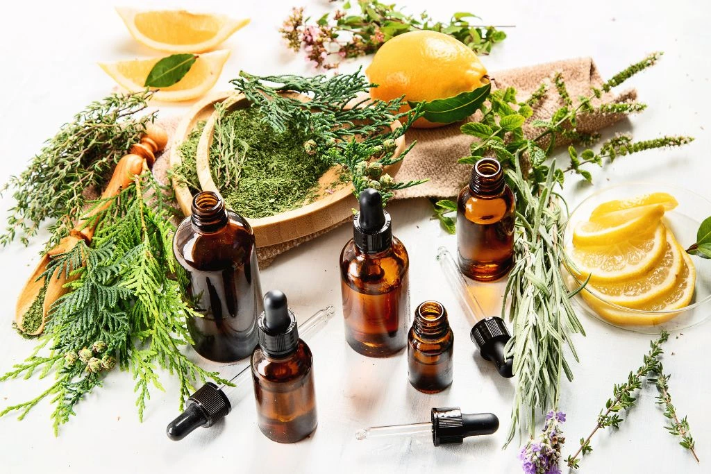 essential oils together with herbs on white table