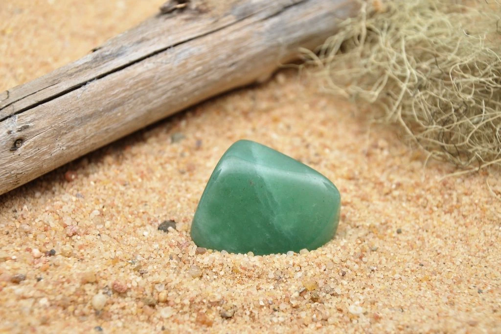 polished green aventurine stone situated on sand