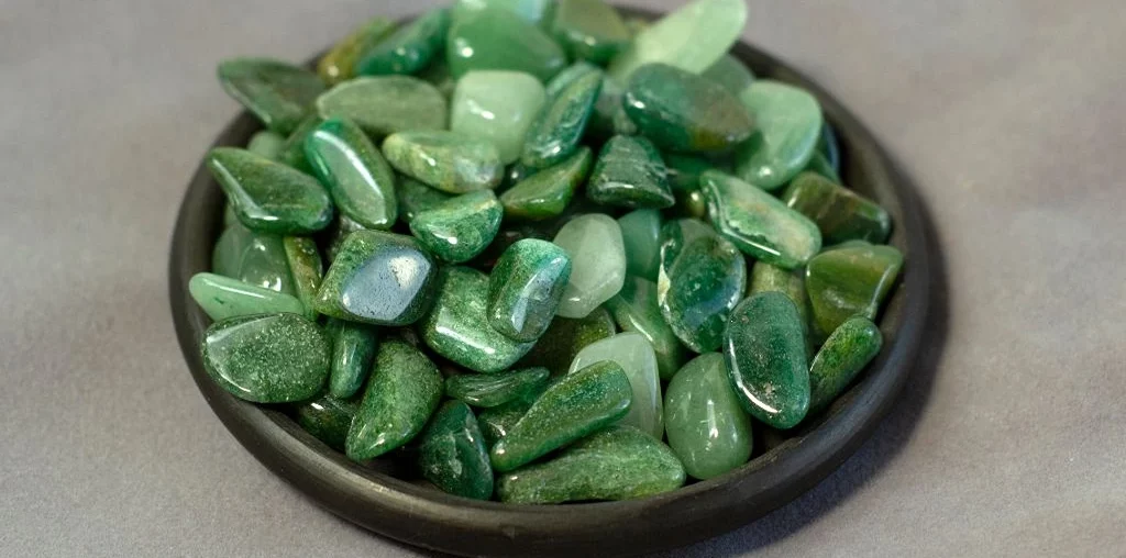 green aventurine stones on a wood brown bowl