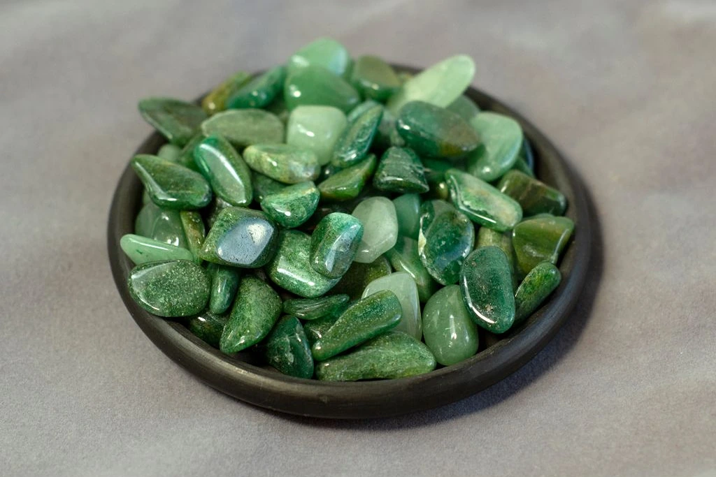 green aventurine stones on a wood brown bowl
