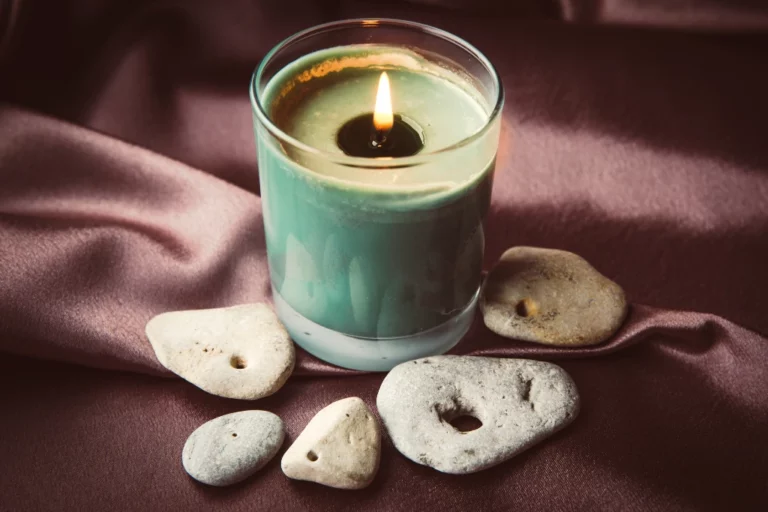 Hag stones surrounding a green candle on a silk cloth