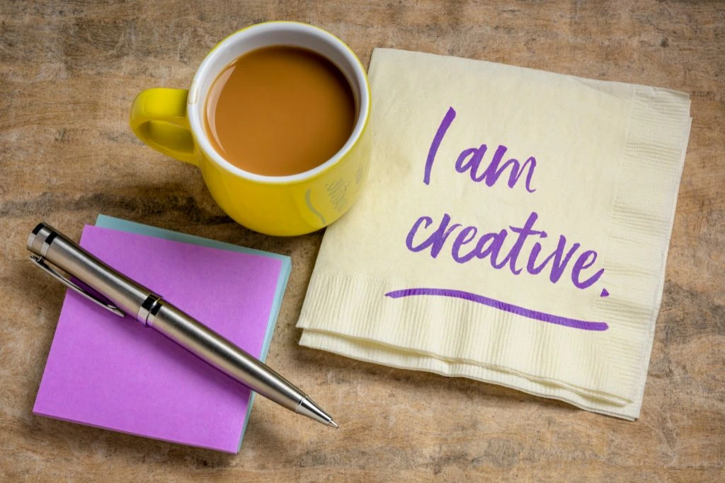  i am creative written on a piece of table napkin together with cup of coffee and sticky notes