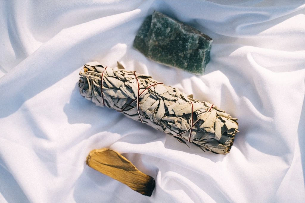 aventurine chunk together with smudging materials for cleansing in a white textile