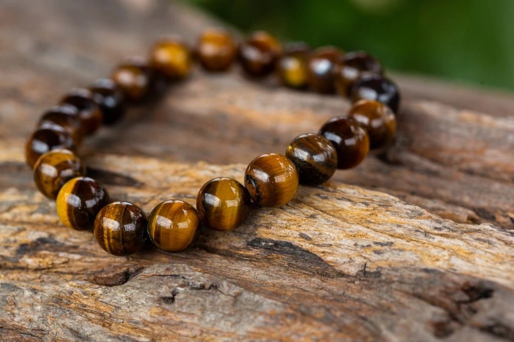 tiger's eye bracelet placed on top of a tree trunk 