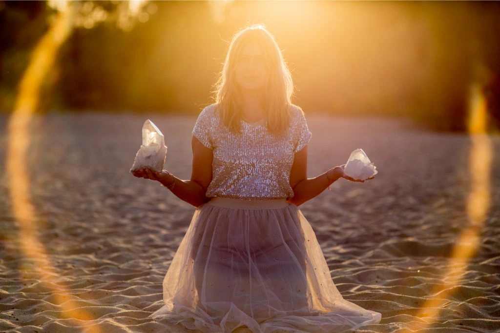 Woman holding selenite crystals while bathing in sunlight at the beach