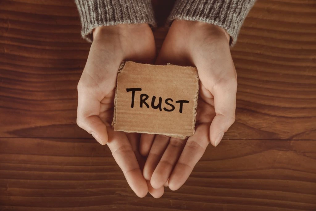 A person holding a carton box with the word trust written on it
