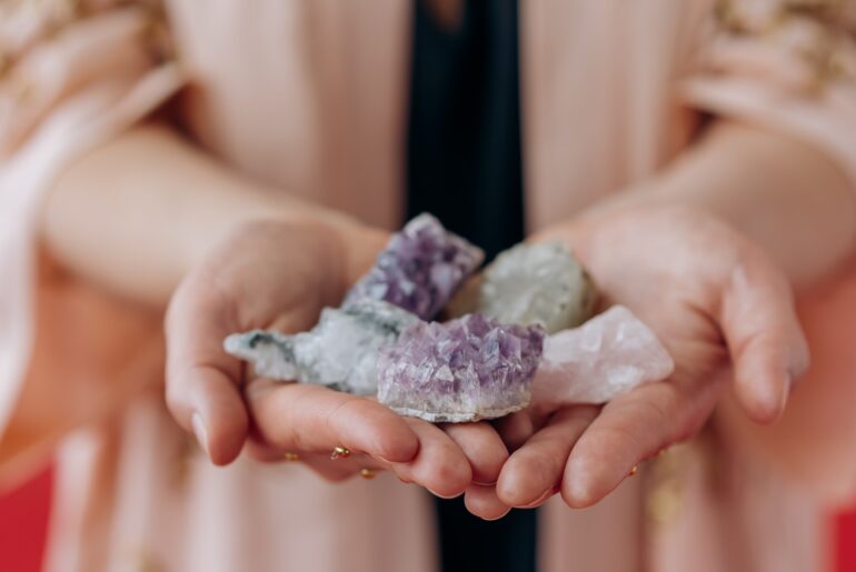 Crystals placed on a hand of a woman wearing pink jacket