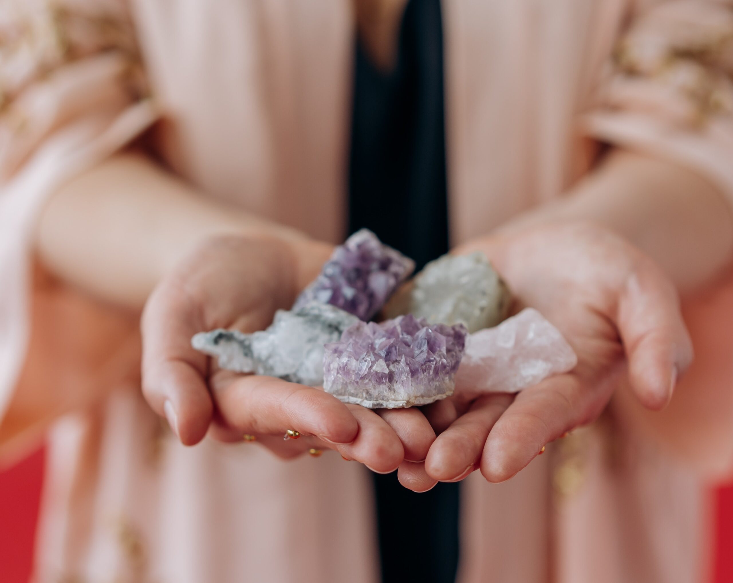 Crystals placed on a hand of a woman wearing pink jacket