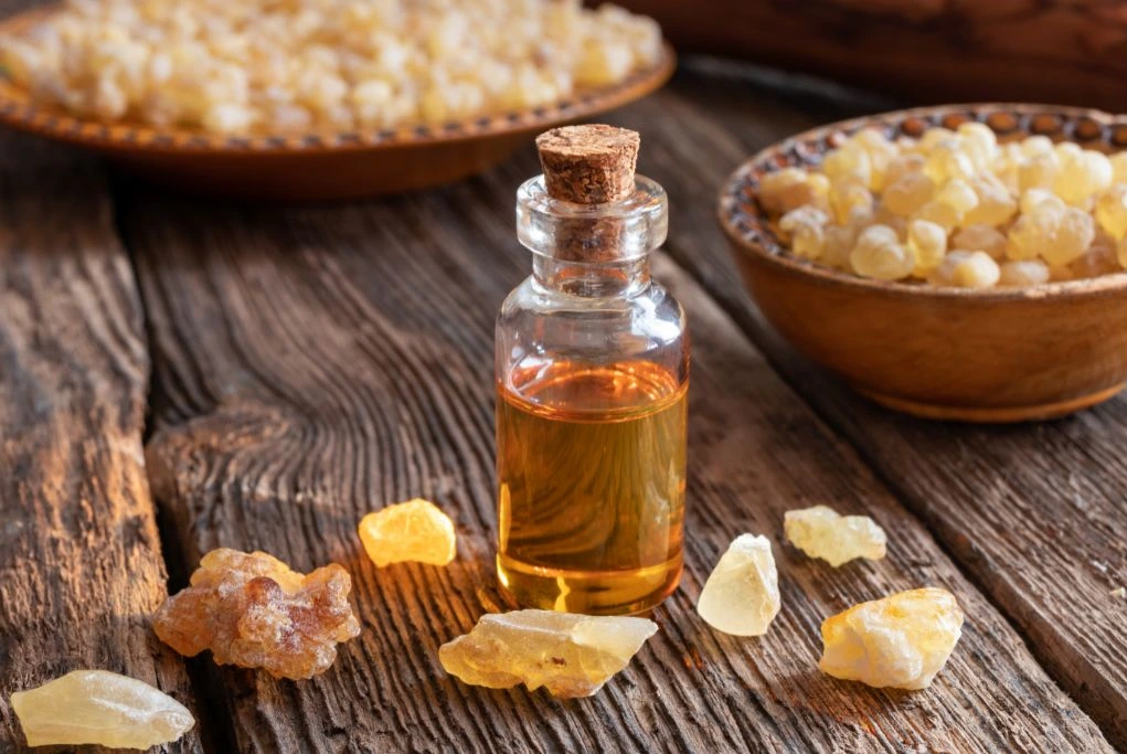 frankincense oil bottle together with small chunks of frankincense on a wooden table