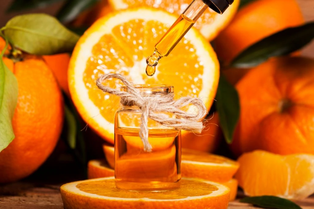 orange essential oil in a bottle placed on top of an orange slice