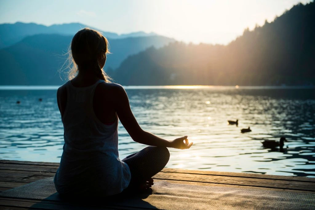 woman meditating facing towards sunrise