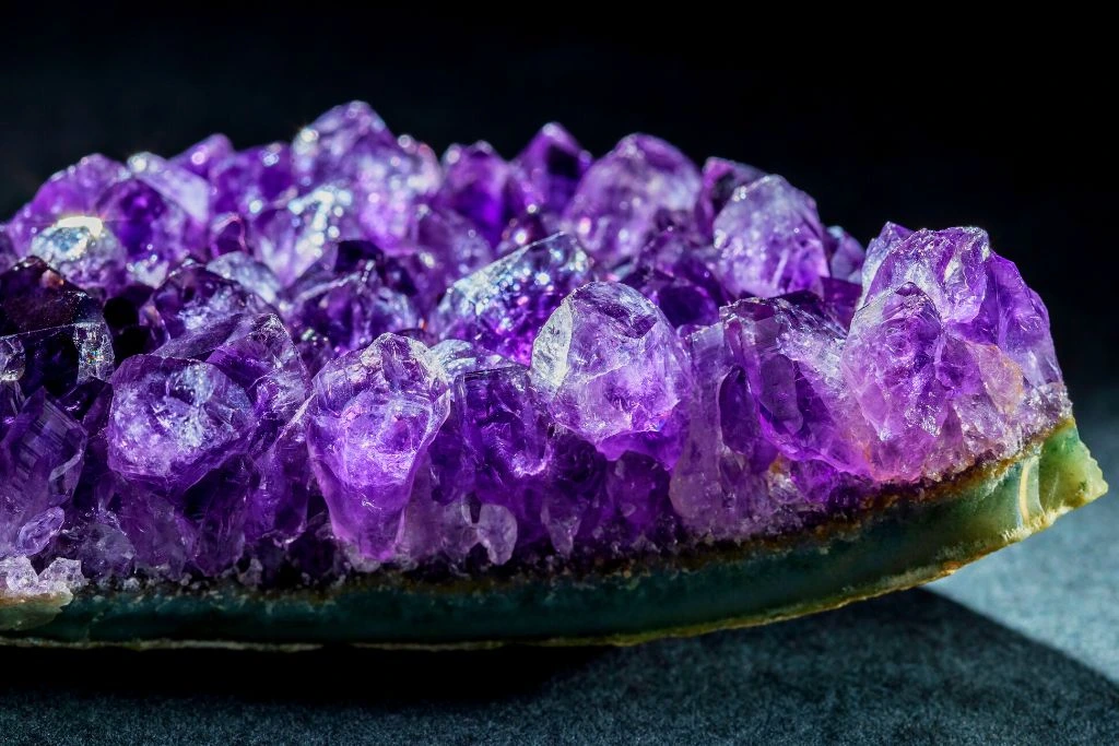 Beautiful and shiny amethyst crystal placed on top of marble surface with a black background