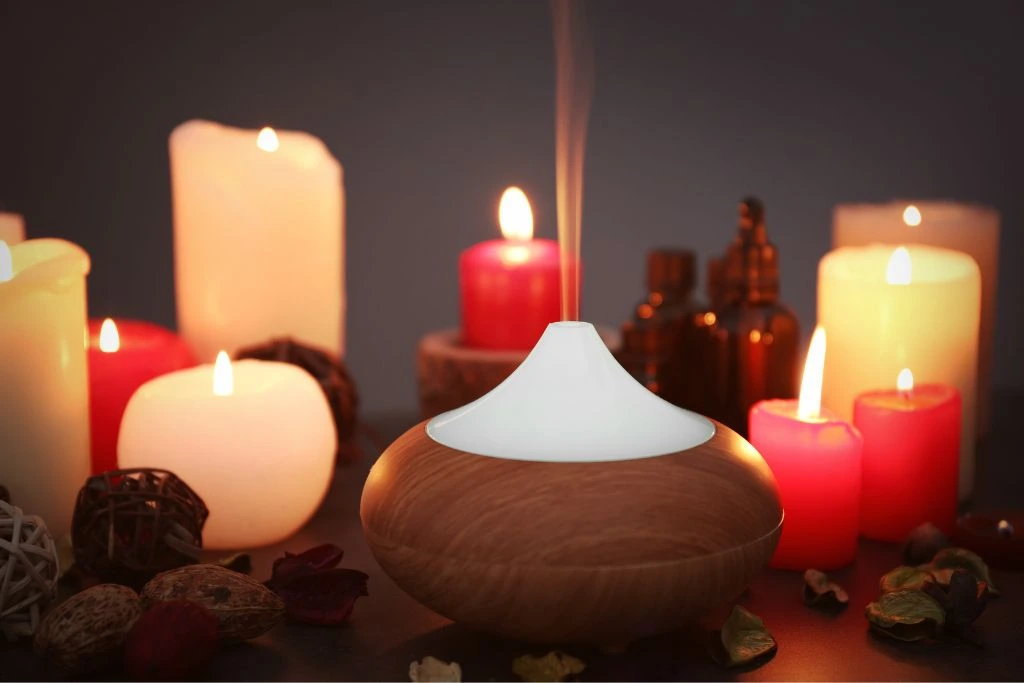 oil burner together with candles adorned with dried leaves and flowers